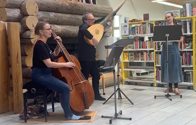 Kuvassa kolme soittajaa kirjaston takan edessä